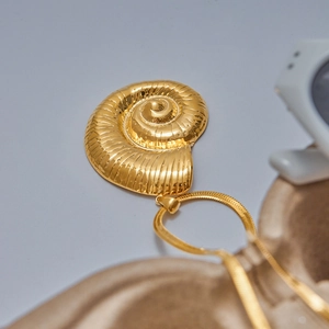 Détail d'un pendentif conque doré avec une chaîne serpent élégante sur une surface douce
