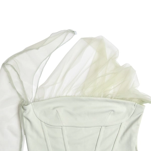Dettaglio del top a bustino verde chiaro con maniche in rete velata e cuciture a corsetto
