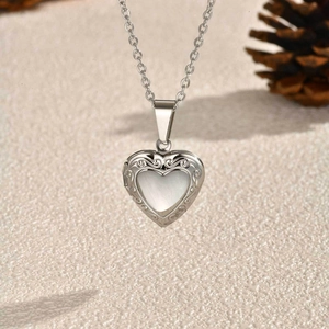 Macro shot of silver heart locket necklace with vintage floral carving and white opal inlay