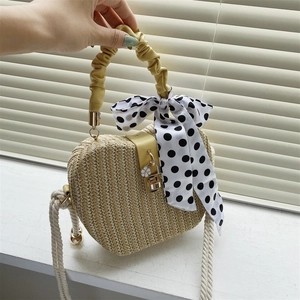Handwoven beige straw crossbody bag with yellow leather handle and polka dot silk scarf