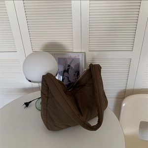 Detailed close-up of brown puffy tote bag on a small table by white window blinds