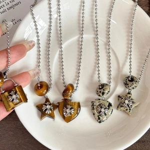 Detailed close-up of tiger eye heart and cross charms on a vintage beaded necklace chain