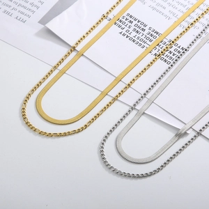 Close-up of gold and silver double-layered snake and Figaro chain necklaces set