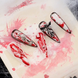 Long stiletto press-on nails with red blood splatters and 3D metal angel charms