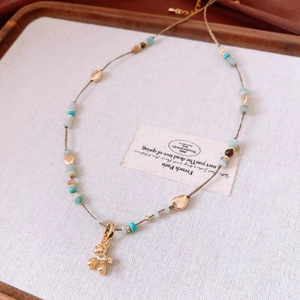 Close-up of stone beaded necklace with a golden puppy pendant on a white fabric tray