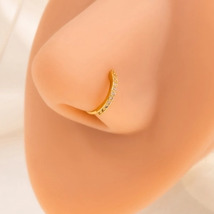 Close-up of sparkling gold C-shaped nose ring with cubic zirconia on a female model