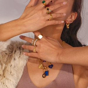 Detail showing layered 18K gold-plated stainless steel necklaces and vintage green gemstone rings