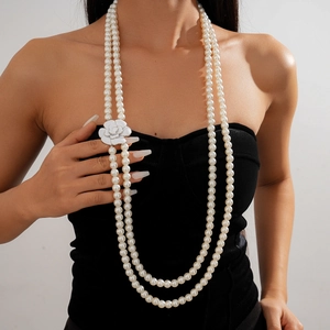 Detail of multilayered pearl necklace with white camellia flower pendant on model