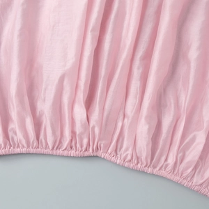 Detail of pink satin shirt hem with elastic shirring and elegant vertical pleats