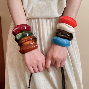 Close-up of stacked acrylic resin bangles in multiple colors on a model's wrist