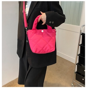 Detail of rose pink quilted nylon crossbody bag shown with adjustable fabric shoulder strap