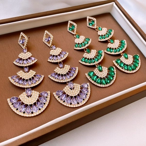 Detail of fan-shaped tassel earrings with purple and green stones in a brown display box