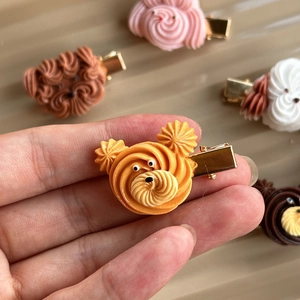 Detail of creative dog-shaped cookie hair clip with cream piping and gold metal grip