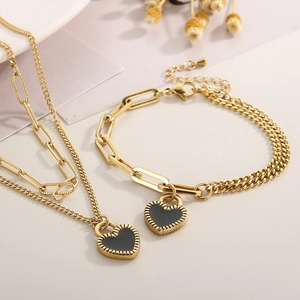 Macro detail of gold double-layer necklace set with black heart-shaped lock pendants