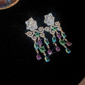 Détail de boucles d'oreilles fleuries avec pierres vertes, bleues et violettes et diamants