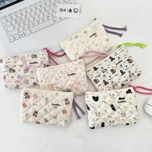 Flat lay of six quilted floral makeup pouches with colorful lanyards on a white desk