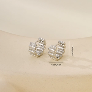 Vue détaillée de boucles d'oreilles créoles argentées avec texture ondulée et fermoir