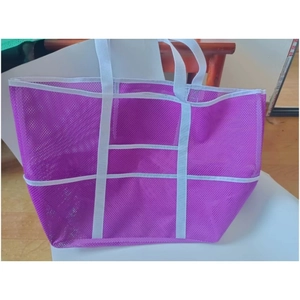 Detailed side view of purple mesh beach bag with white strap handles and storage pockets