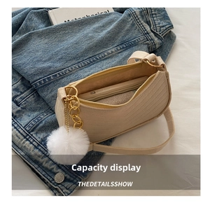 Détail montrant la capacité intérieure du sac baguette beige avec chaîne dorée et pompon