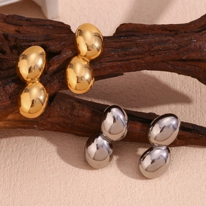 Detail view of peanut-shaped 18K gold and silver plated earrings on wood texture