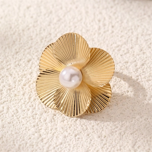 Macro shot of a golden flower ring featuring textured petals and a central white pearl