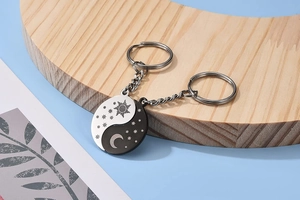 Close-up of sun and moon couple keychains on a crescent wooden tray with star details
