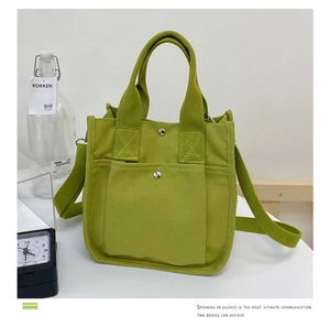 Detail view of the grass green canvas tote bag featuring front pockets and sturdy handles