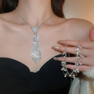 Detail of silver tie-shaped necklace with rhinestones and pearl tassel on a model