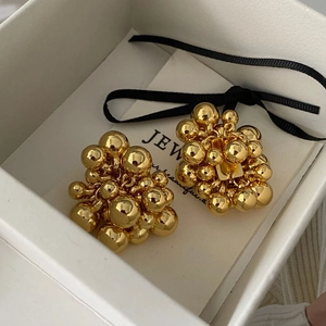 Close-up of golden cluster stud earrings in a white gift box with black ribbon bow