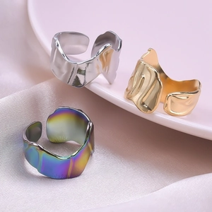 Irregular textured open ring in silver, gold, and iridescent finishes on satin fabric