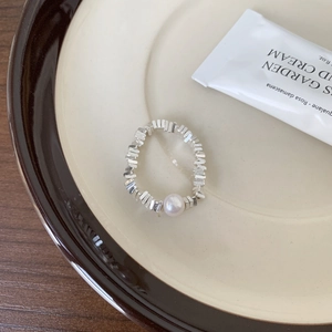 Detail of 925 sterling silver chain ring with white pearl on a ceramic plate