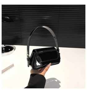 Macro detail of the glossy black patent leather material on this modern underarm bag