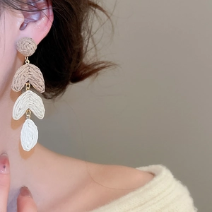 Macro detail of multi-layered raffia tassel earrings on model for a beach vacation style