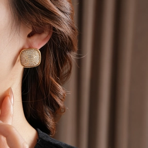 Close-up of gold square stud earrings with micro-set zircon on model's ear