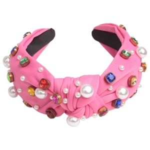 Detailed view of pink fabric knotted headband with white pearls and colorful gemstones