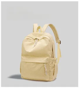 Detail of yellow corduroy backpack featuring elastic side pockets and textured fabric