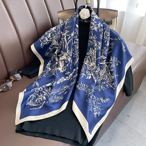 Dettaglio di un foulard in seta blu con stampe di animali drappeggiato su un top nero su pelle