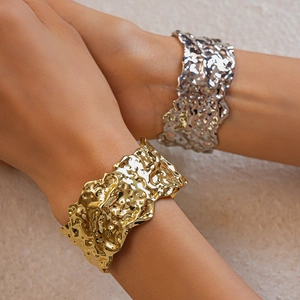 Close-up of metallic textured cuff bracelets with irregular hammered finish on model