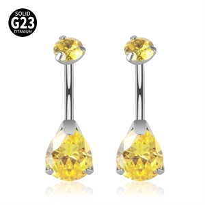 Dettaglio macro del piercing all'ombelico in titanio G23 con pietre di zircone giallo