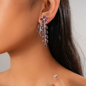 Close-up of vintage purple flower and leaf tassel earrings worn by a female model