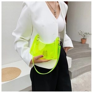 Neon green transparent PVC shoulder bag styled with a minimalist white suit outfit