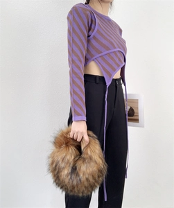 Detail of a brown faux raccoon fur handbag styled with a purple striped y2k knit top