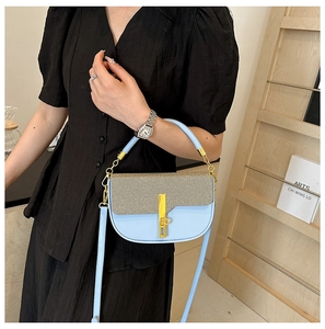 Detail of light blue handbag featuring beige woven texture and gold metal lock clasp