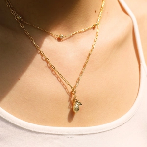 Collier double rang en or avec pendentif ananas présenté sur le cou d'un mannequin