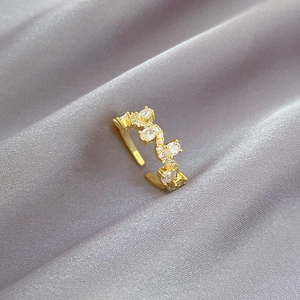 Gold adjustable branch ring with white zircons on a gray silk background from a 45-degree angle