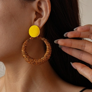 Detail of gold circular textured hoop earrings with yellow stud on female model