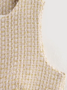 Close-up of beige and white tweed fabric woven with elegant gold metallic threads