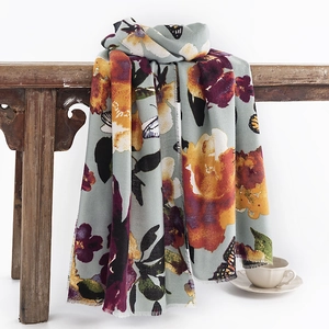 Butterfly and rose print cashmere feel scarf with fringe on a rustic wooden stool