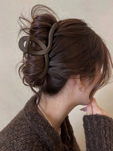 Detail view of a matte dark brown shark hair claw clip worn by a model from the side