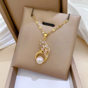 Detailed close-up of golden peacock pendant with sparkling zircons and a white pearl